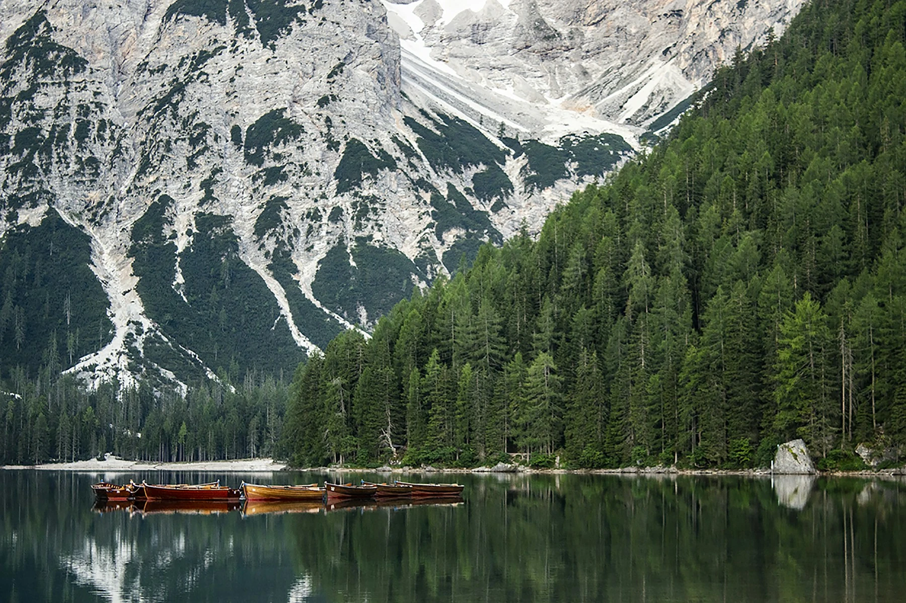 Wooden boats on a turquoise lake beneath the Dolomites
